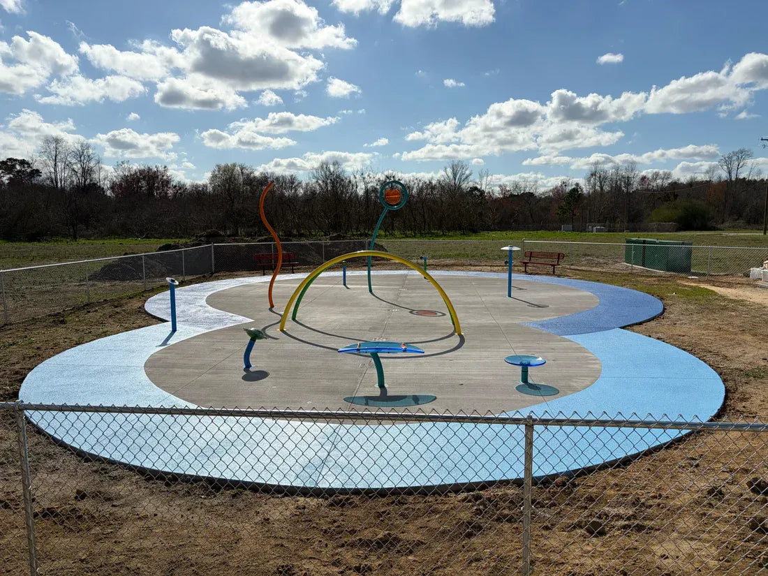 Playground structure with colorful equipment on a grassy area under a blue sky with clouds.